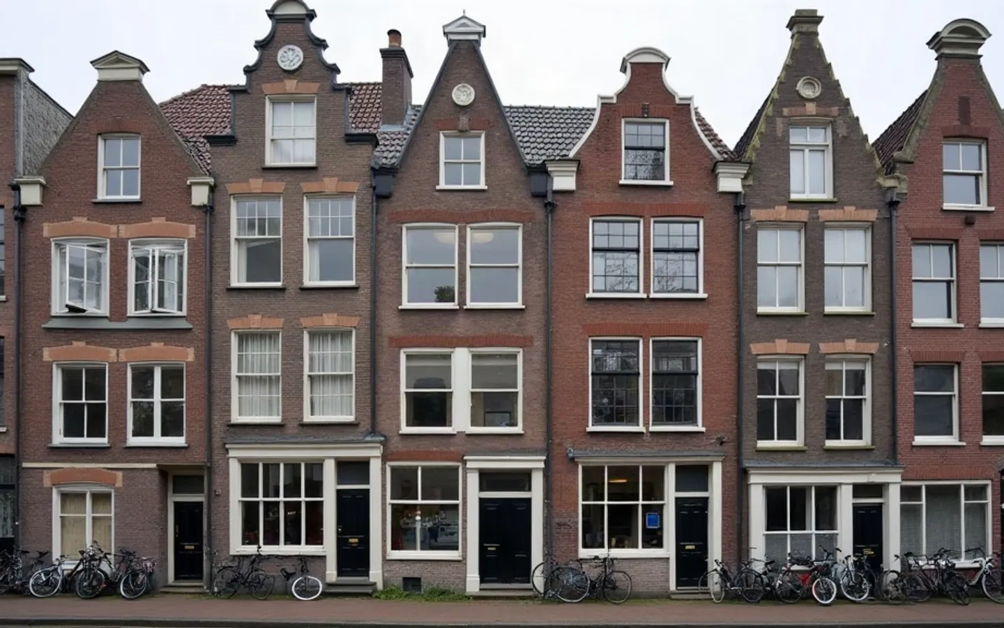 Een breed pand met veel ramen en meerdere bellen naast de voordeur.
